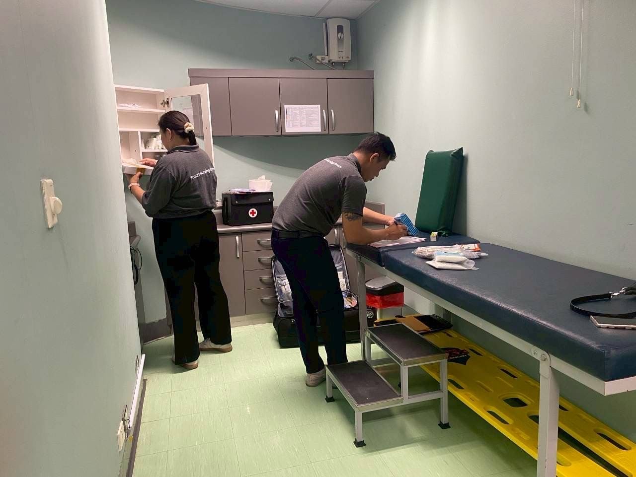 Two W-Asia staff restocking medicine and supplies in an on-site company first-aid room